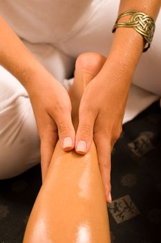 Therapist massaging a female thigh on a oriental mat