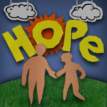 A paper and cardboard cutout diorama with the word Hope in front of the sun with clouds in the sky and two people - and adult and child - holding hands on grass