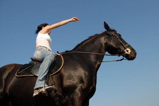 young woman and her black stallion in a field