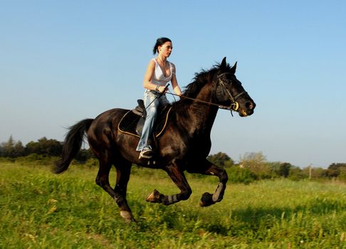 young woman and her black stallion in a field