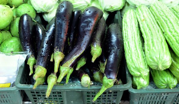 Baskets of cabbage and purple eggplant brighten a farmers market. 