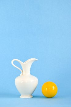white vase and yellow ball on azure background