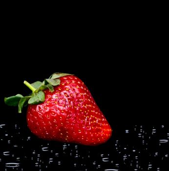 fresh strawberry with water drops on black background