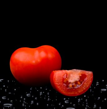 Tomato with water drops on black background