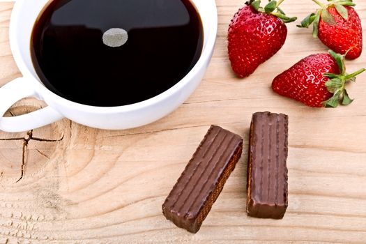 Strawberry with a cup of coffee and chocolate on wood