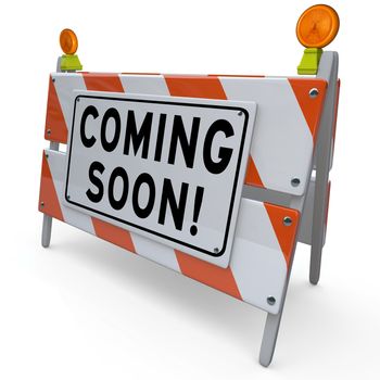 An orange and white construction barricade sign with the words Coming Soon to announce and introduce or give a sneak preview of a new feature, road project, business, event or other object