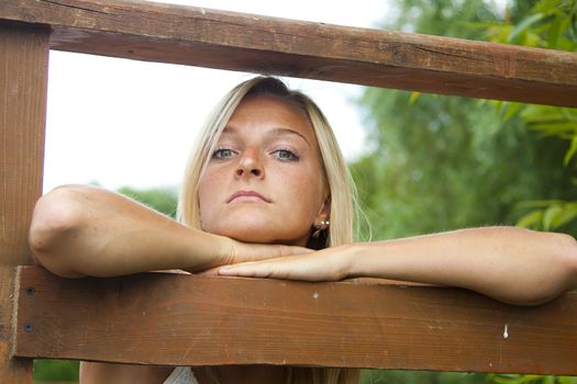 Young and beautiful woman on the pier by the forest lake