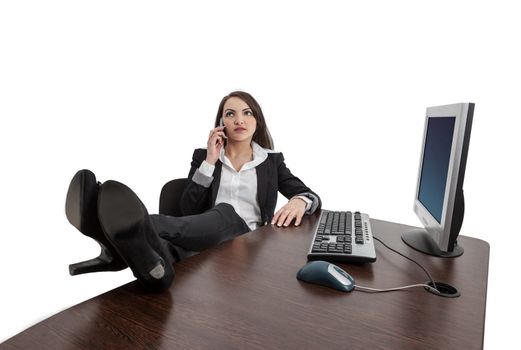 Relaxed businesswoman with her legs on the desk using a mobile phone, against a white background.