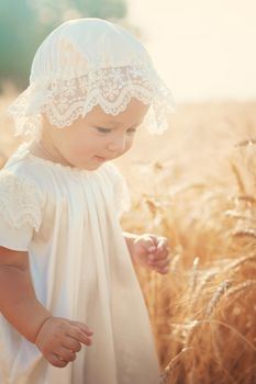 Laughing kid in sunny wheat  field in vintage dress