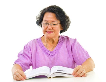 Asian senior woman serious reading book over white background