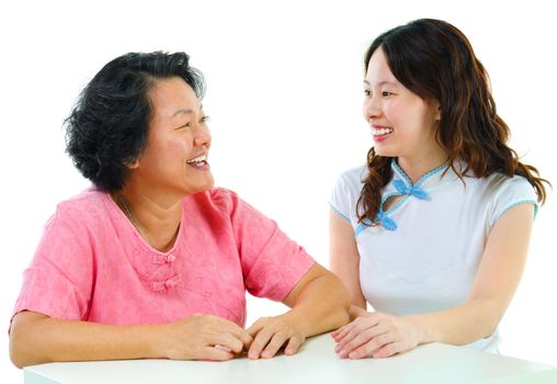 Adult daughter having conversation with senior mother indoor.