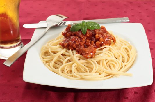 dish of noodles with tomato sauce and minced meat with a few basil leaves