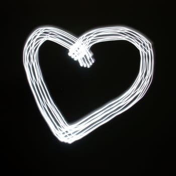 Heart symbol created by light over black background