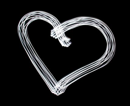 Heart symbol created by light over black background