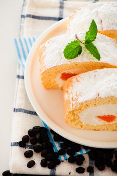 Sponge roll cake with orange cream and fresh mandarin. Fresh ,mMint and icing sugar as decoration on the top.