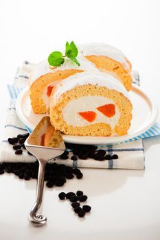 Sponge roll cake with orange cream and fresh mandarin. Fresh ,mMint and icing sugar as decoration on the top.