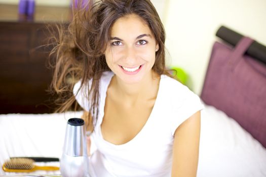 Smiling cute girl dry her hair at home in bed