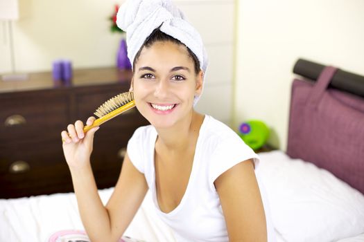 Happy girl with brush and towel on hair in bed