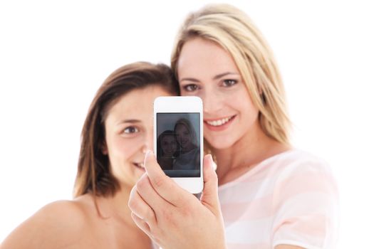 Two attractive young women standing close together holding up their mobile phone with the screen displaying their photograph Two attractive young women standing close together holding up their mobile phone with the screen displaying their photograph