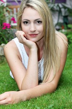 Portrait of a beautitul young blonde woman lying on her stomach on lush green summer grass Portrait of a beautitul young blonde woman lying on her stomach on lush green summer grass