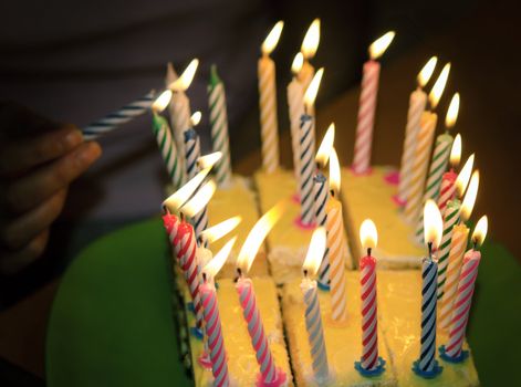 A birthday cake with lighted candles .Focus is on the candles.