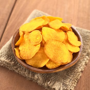 Crispy Peruvian sweet potato chips on wooden plate (Selective Focus, Focus on the lower part of the sweet potato chips)