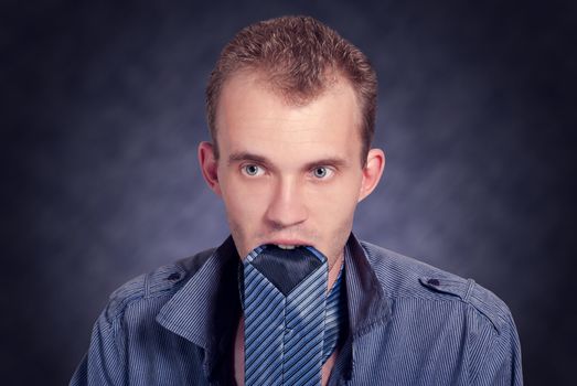 Elegant man with a tie in the mouth. Fashion studio photo.