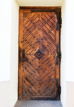 Old wooden door with rusty hinges and handle