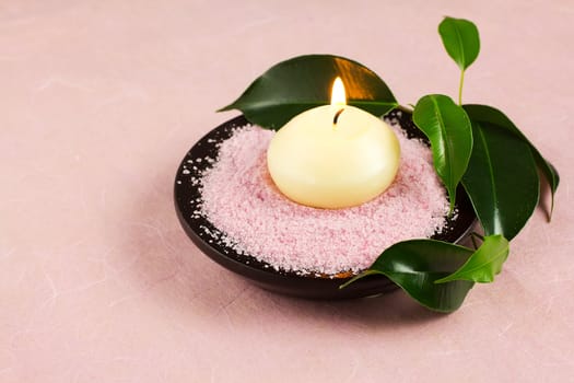 Candle,  green leaves,  sea salt, pink background.