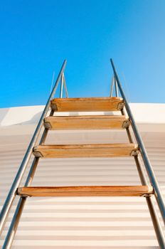 Ladder to the blue sky on white yacht wall