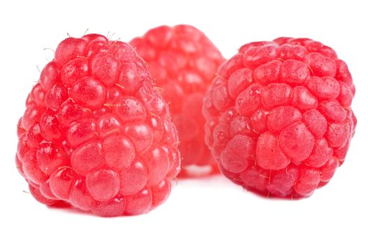 Group of three red raspberries on a white background
