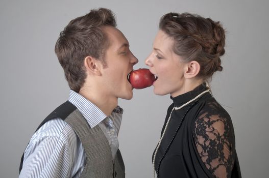 girl and young man bite together red apple