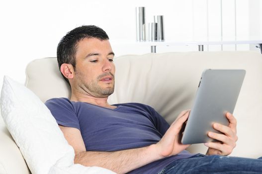 attractive relaxed and positive man is surfing on his tablet