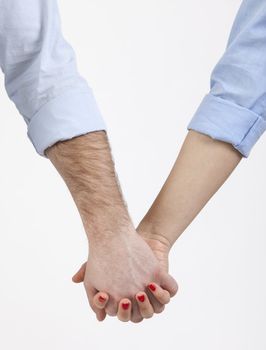 Close-up image of a couple holding hands with turned up sleeves.