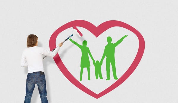 Young man with a paintbrush and family picture on the wall