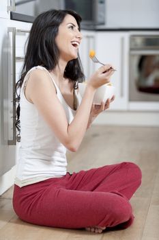 Young woman enjoying a bowl of fresh fruit in her kitchen