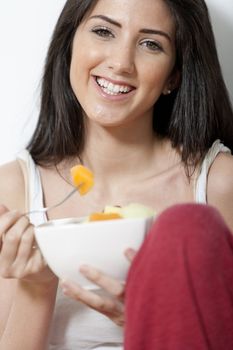 Young woman enjoying a bowl of fresh fruit in her kitchen