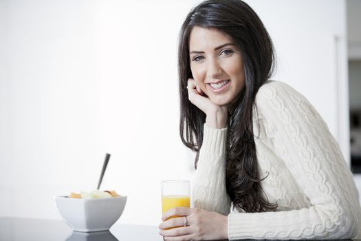 Young woman in kitchen enjoying some orange juice and fresh fruit