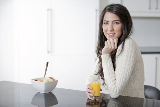 Young woman enyoying a bowl of fresh fruit in her kitchen