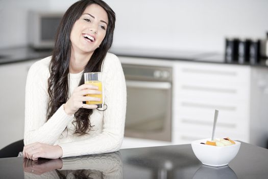 Young woman in kitchen enjoying some orange juice and fresh fruit