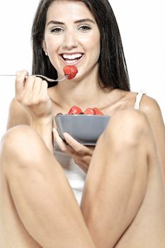 Beautiful young woman enjoying fresh fruit for breakfast at home