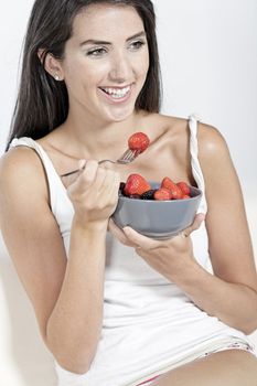 Beautiful young woman enjoying fresh fruit for breakfast at home