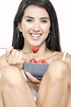 Beautiful young woman enjoying fresh fruit for breakfast at home