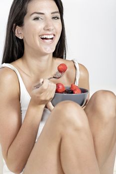 Beautiful young woman enjoying fresh fruit for breakfast at home