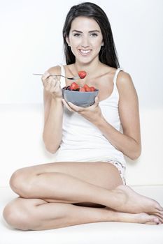 Beautiful young woman enjoying fresh fruit for breakfast at home