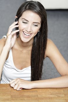 Beautiful young woman talking on her mobile phone at home