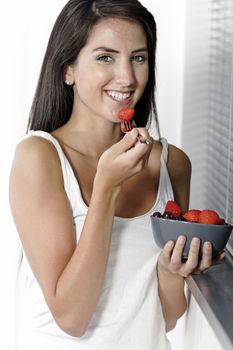 Beautiful young woman enjoying fresh fruit for breakfast at home