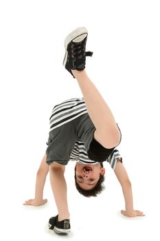 Attractive happy boy doing cartwheel on white floor.