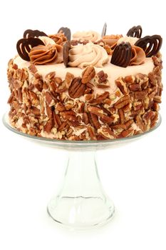 Decorated Pecan Caramel Chocolate Cake on Glass Display Platter over White Background