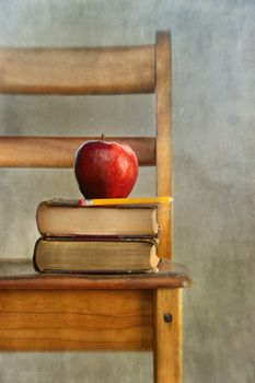 Apple and old books on school chair with vintage feel